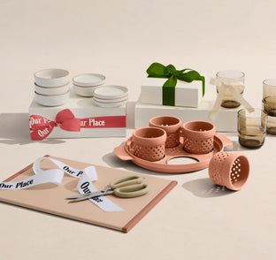 Table setting with ceramic and glass items, including cups and a cutting board, on a neutral background.