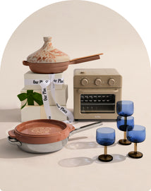 Set of ceramic cookware with a small oven and decorative glasses on a neutral background